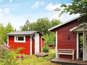 a red cabin with a bench in front of it at 4 person holiday home in Åsljunga in Åsljunga