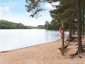 a bench on a beach next to a body of water at 4 person holiday home in Åsljunga in Åsljunga