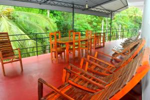a deck with wooden chairs and a wooden table and benches at Eco Transit Udawalawe in Udawalawe