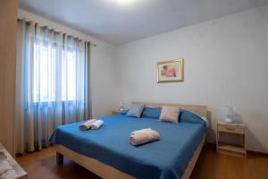 a bedroom with a blue bed with two towels on it at Apartments Soni in Postira