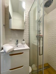 a white bathroom with a sink and a shower at Apartament Bałtycki in Jastrzębia Góra