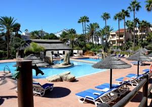 a swimming pool with lounge chairs and umbrellas at SANTA CRUZ SUITE Jardín con vistas Mijas Costa in Málaga