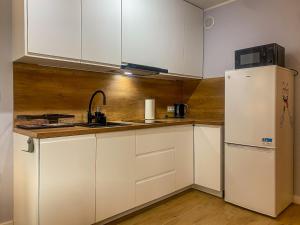 a kitchen with white cabinets and a refrigerator at Apartament Bałtycki in Jastrzębia Góra +6 photos