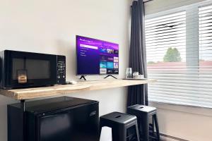 a desk with a microwave and a television and stools at Levis Center New Studio #2 AC, WiFi and 2 Parking spaces in Lévis
