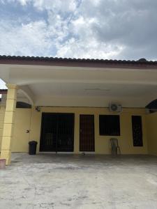 a large yellow building with two doors and a chair at Nadis Guesthouse in Ipoh