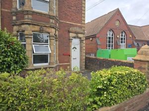 a brick house with a white door and a church at Comfortable Room 4 in Avonmouth