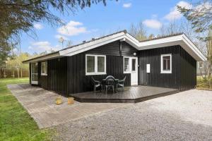 ein schwarzes Tiny House mit Holzterrasse in der Unterkunft 1419 Aakirkeby - Boesparken 16 in Vester Sømarken