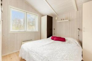 ein Schlafzimmer mit einem weißen Bett mit einem roten Kissen in der Unterkunft 1419 Aakirkeby - Boesparken 16 in Vester Sømarken