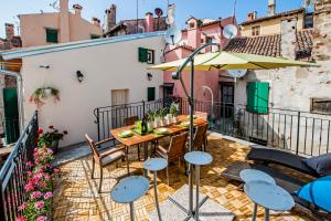 eine Terrasse mit Tisch und Stühlen und einem Sonnenschirm in der Unterkunft Casa Smeralda in Rovinj