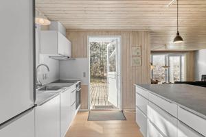 eine Küche mit weißen Schränken und einer Tür zu einem Hof in der Unterkunft 1542 Aakirkeby - Poseregårdsvejen 12 in Vester Sømarken
