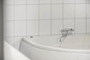 ein Badezimmer mit einer Badewanne und einer weiß gefliesten Wand in der Unterkunft 1542 Aakirkeby - Poseregårdsvejen 12 in Vester Sømarken + 14 Fotos
