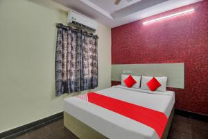a bedroom with a bed and a red wall at Hotel O Lavish Stay in Hyderabad