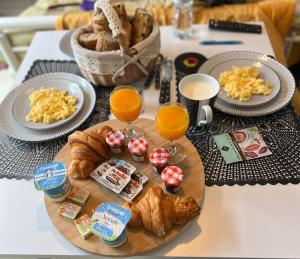 a table with a tray of breakfast food and orange juice at Séjour près de Bayeux avec Massages et repas en options in Tilly-sur-Seulles
