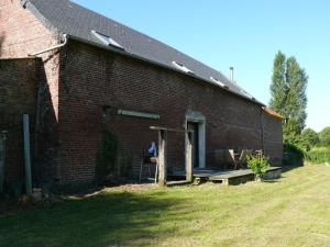 a brick building with a porch with a person sitting on it at Ferme renel in Poses