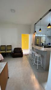 a kitchen and living room with a counter and chairs at Casa na praia 6 camas e 4 colchoes in Mongaguá