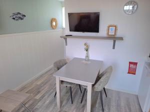 a white table with chairs and a tv on a wall at Appartement vlakbij strand en centrum in Zoutelande +4 photos