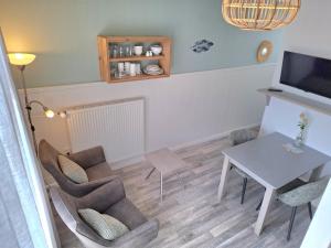 a living room with a table and chairs and a television at Appartement vlakbij strand en centrum in Zoutelande