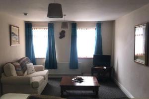 ロンドンデリーにあるCentral 2-Bed Apt Sleeps 5 above Great Derry Pubのソファとテーブルのあるリビングルーム +2枚の写真