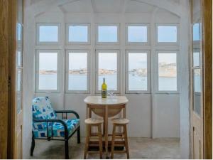 a table and chairs in a room with windows at SeaFront Apartment In Valletta in Valletta