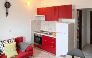 a small kitchen with red cabinets and a red couch at Amazing Apartment In Supetar in Supetar