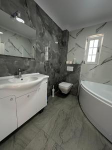 Un baño con lavabo, bañera e inodoro. en Vila Bran, en Corneşti