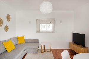 a living room with a gray couch and a television at Estoril Beach - Your Family Escape in Estoril