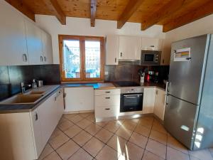 a kitchen with white cabinets and a stainless steel refrigerator at Chalet spacieux avec vue magnifique in Saint-Marcel +11 photos