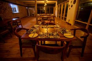 a wooden table in a restaurant with plates and glasses on it at Burunga Gorilla Lodge in Kisoro