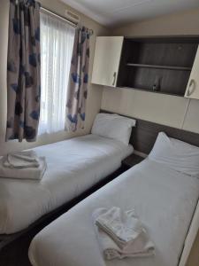 two beds in a small room with a window at Valley side - 3 bedrooms sleeps 8 in Burmarsh