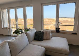 a living room with a couch and large windows at Duinzicht in Westende-Bad