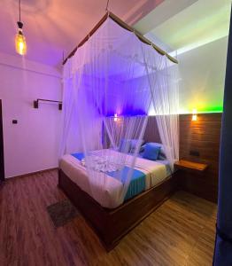 a bedroom with a canopy bed with purple lights at Crest Cold Homestay in Ella