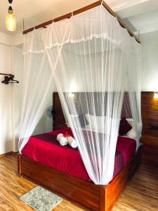 a bedroom with a red bed with a canopy at Crest Cold Homestay in Ella