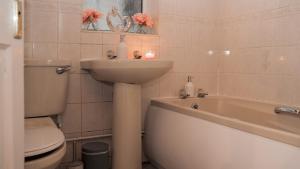 a bathroom with a sink and a toilet and a bath tub at Lovely 2 Bedroom Home Coventry in Tollbar End +8 photos
