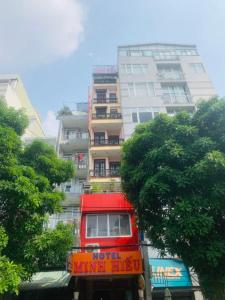 a red double decker bus in front of a tall building at Hotel Minh Hiếu in Ho Chi Minh City