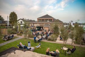 a group of people sitting in the grass in front of a building at Hemhuisje in Zaandam