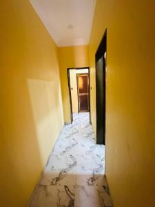 a hallway with yellow walls and a marble floor at RESIDENCE PHs 2 in Ouagadougou