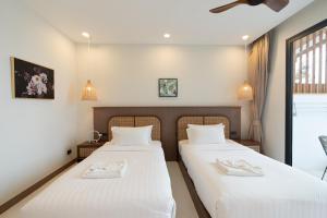 two beds in a room with white sheets at ENNKAI Beachfront Resort Koh Larn in Pattaya