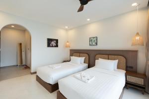 two beds in a hotel room with white sheets at ENNKAI Beachfront Resort Koh Larn in Pattaya Central