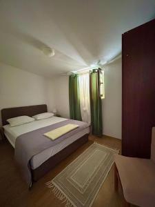 a bedroom with a large bed with green curtains at Apartments Kety in Jezera