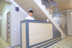 a man standing behind a blank board in a staircase at Guest House Silver in Samarkand
