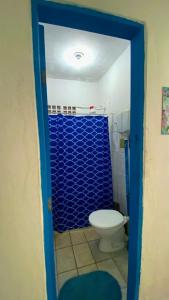 a bathroom with a toilet and a blue shower at Casinha Blue Pipa in Pipa