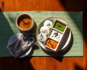 a table with a plate of food and a bowl of soup at MeruVann, Kanha National Park in Bhimlath +6 photos
