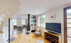 a living room with a television and a staircase at Au bord de l'Odon in Louvigny