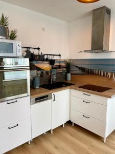 a kitchen with white cabinets and white appliances at Möwennest in Nienhagen +23 photos