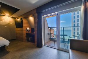 een slaapkamer met een balkon met uitzicht op de oceaan bij Moonbay Hotel in Busan