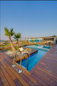a swimming pool with palm trees and a wooden deck at VENTO MARE LUXURY Hotel in Cesme