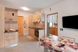 a kitchen with a table and a tv on a wall at Appartamento Nuovo A San Giovanni in Pozza di Fassa +23 photos
