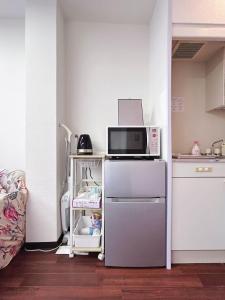 a small kitchen with a microwave and a refrigerator at Ueno-Tokyo Garden in Tokyo