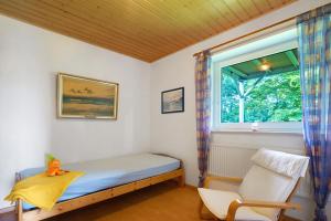 a bedroom with a bed and a window and a chair at Ferienhof Kiesow in Nordstrand