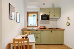 cocina con armarios verdes, mesa y fregadero en Casa Nonna Gina, en Génova 21 fotos más